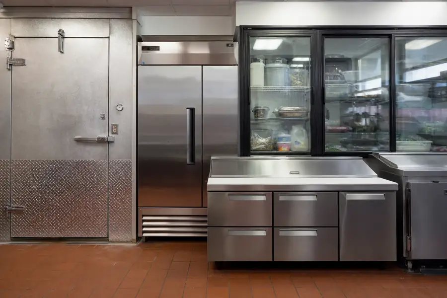 Editorial hero photograph for a commercial foodservice refrigeration article titled “Door and Seal Maintenance Across a Commercial Kitchen.” Show One representative door photograph per unit type, ideally all from Boulder County jobs. Relevant equipment: Walk-ins; reach-ins; prep tables; drawers; glass display; undercounter; back-bar; merchandisers. Relevant manufacturers when naturally visible: Contextual across all 22. Use an authentic restaurant, grocery, school-kitchen or foodservice setting, natural practical lighting, realistic wear and materials, documentary composition, no staged corporate poses, no added text, 16:9 landscape. When the brief requires technical proof, publication should use a real job-site photo instead of an invented representation.