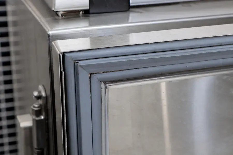 High-detail documentary for “Door and Seal Maintenance Across a Commercial Kitchen.” Show the key commercial refrigeration gasket, door-seal, measuring, diagnostic or hardware detail involved in “Door and Seal Maintenance Across a Commercial Kitchen”. Focus on the gasket profile, mitre, magnetic strip, retaining channel, hinge, latch, measurement point or visible failure pattern that supports the article’s explanation. Relevant equipment: Walk-ins; reach-ins; prep tables; drawers; glass display; undercounter; back-bar; merchandisers. Relevant manufacturers when naturally visible: Contextual across all 22. Realistic commercial-kitchen surfaces, accurate proportions, no added labels or text, horizontal composition.