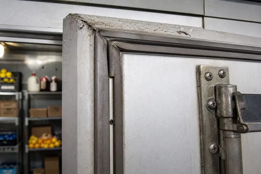High-detail documentary for “The Walk-In Door Maintenance Checklist for Commercial Kitchens.” Show the PDF cover. Focus on the gasket profile, mitre, magnetic strip, retaining channel, hinge, latch, measurement point or visible failure pattern that supports the article’s explanation. Relevant equipment: Walk-in coolers and freezers. Relevant manufacturers when naturally visible: Kolpak, Nor-Lake, Master-Bilt, Bally. Realistic commercial-kitchen surfaces, accurate proportions, no added labels or text, horizontal composition.